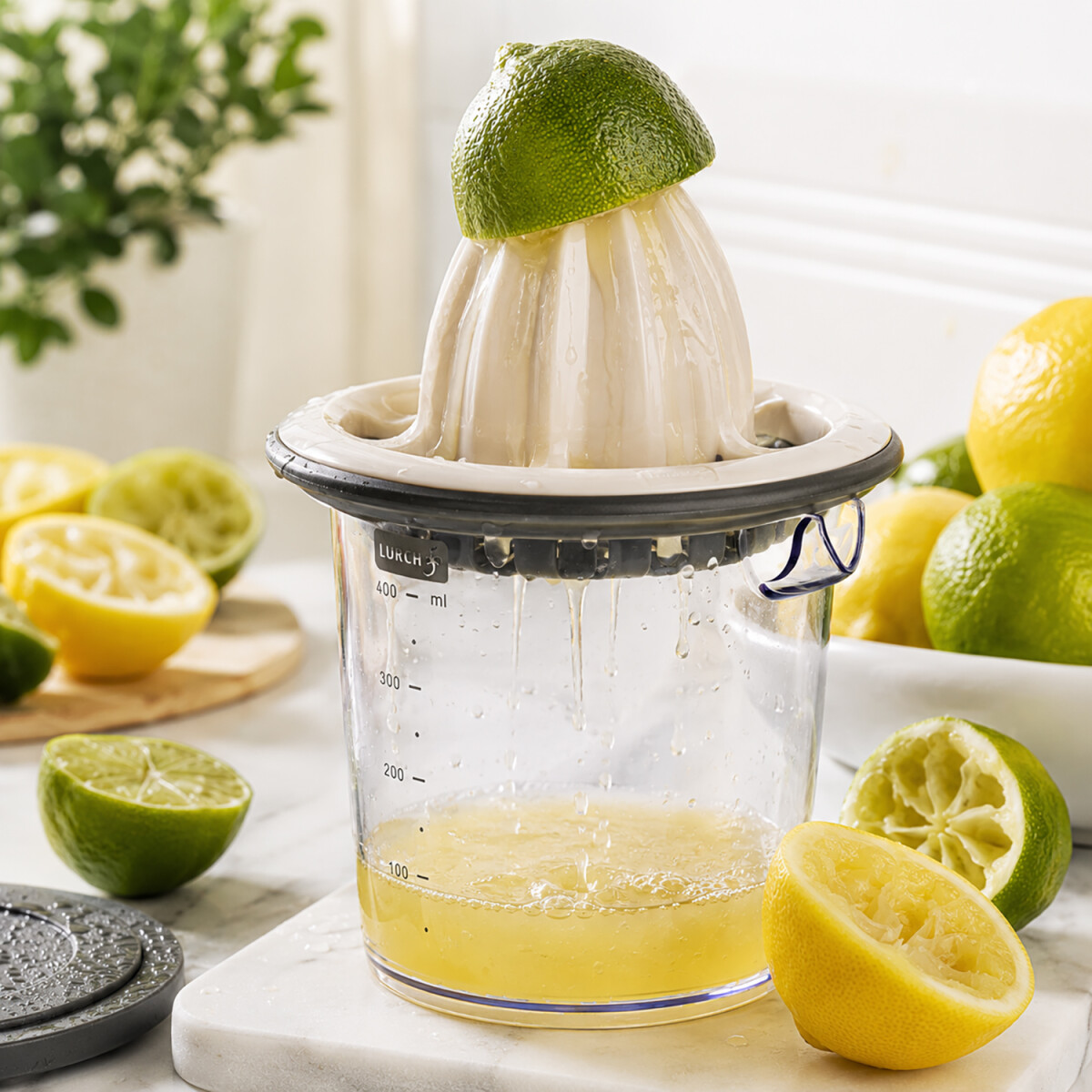 Frischer Zitronen- und Limettensaft l&auml;uft in die originale LURCH Zitruspresse mit sichtbaren Wassertropfen